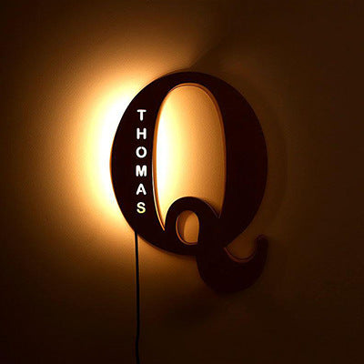 Decorative wall light with 'THOMAS' on a dark background