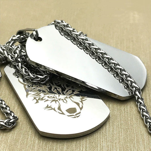 Two silver dog tags with a wolf engraving on a beige background