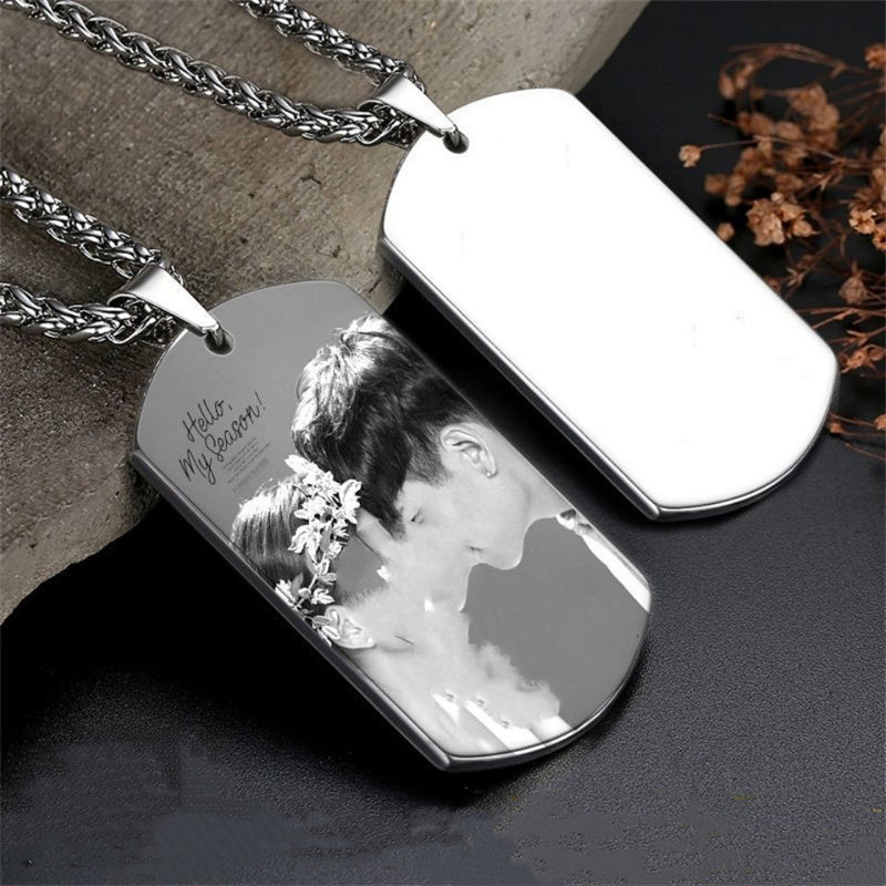 Silver dog tag with engraved photo and text on a dark surface