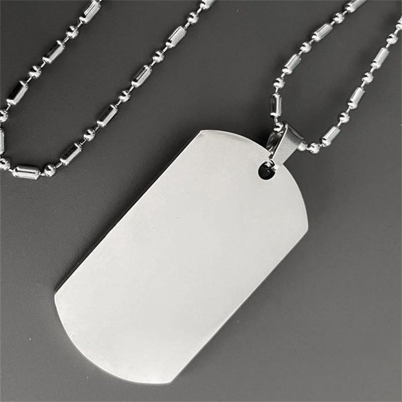 Silver dog tag pendant on a chain against a dark background