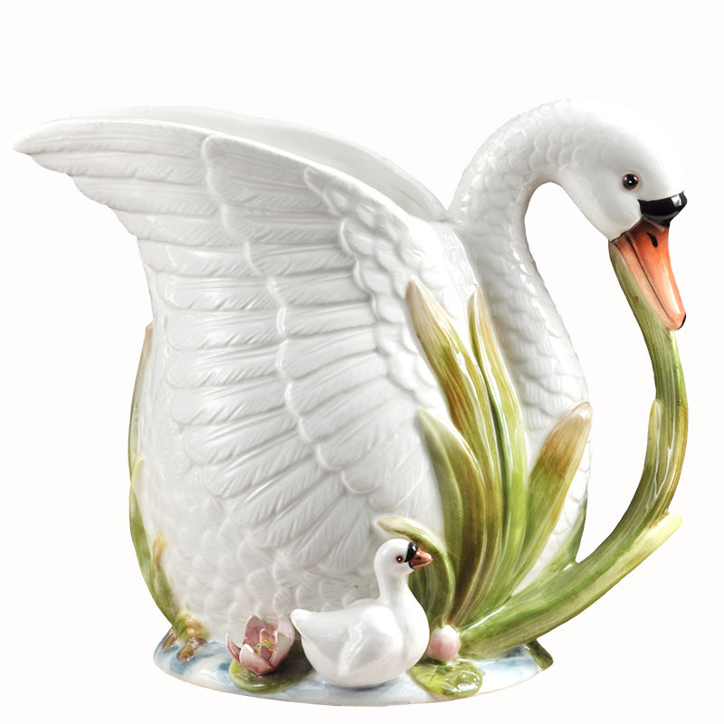 Ceramic swan figurine with a smaller swan and duckling on a white background