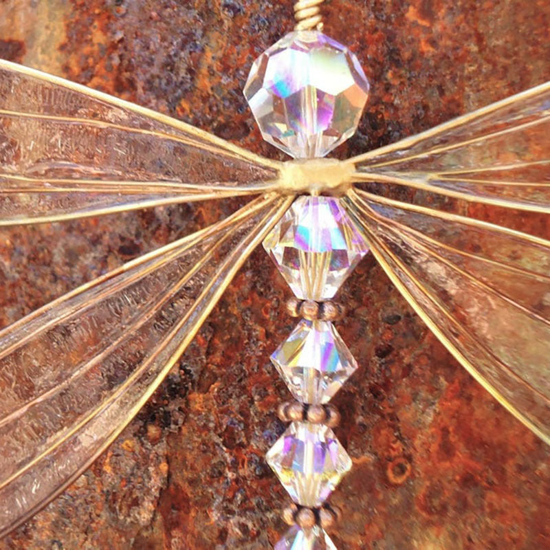 Decorative butterfly charm with crystal-like beads on a rusted metal background