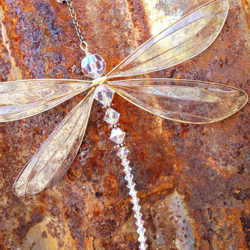 Decorative dragonfly ornament with crystals on a rusted metal surface