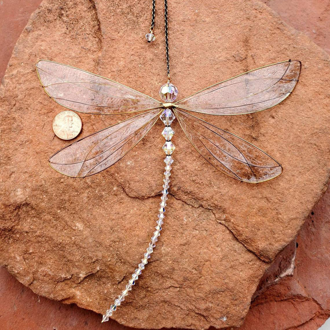 Dragonfly-shaped pendant with beads on a rock