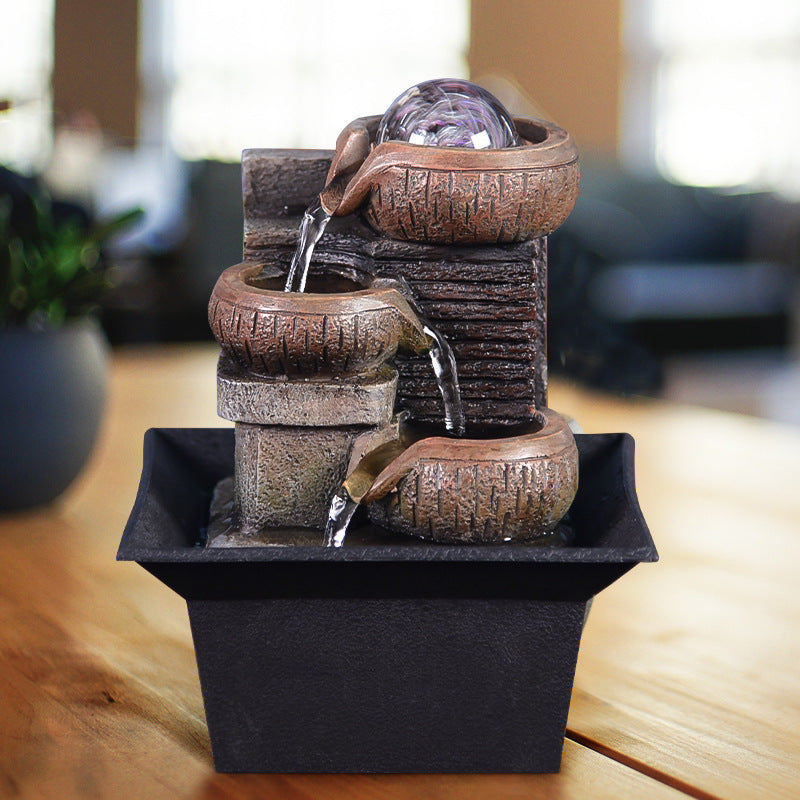 Decorative water fountain with tiered bowls on a wooden surface