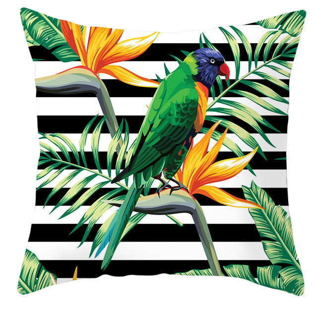 Decorative pillow with a tropical design featuring a parrot, flowers, and leaves on a black and white striped background.