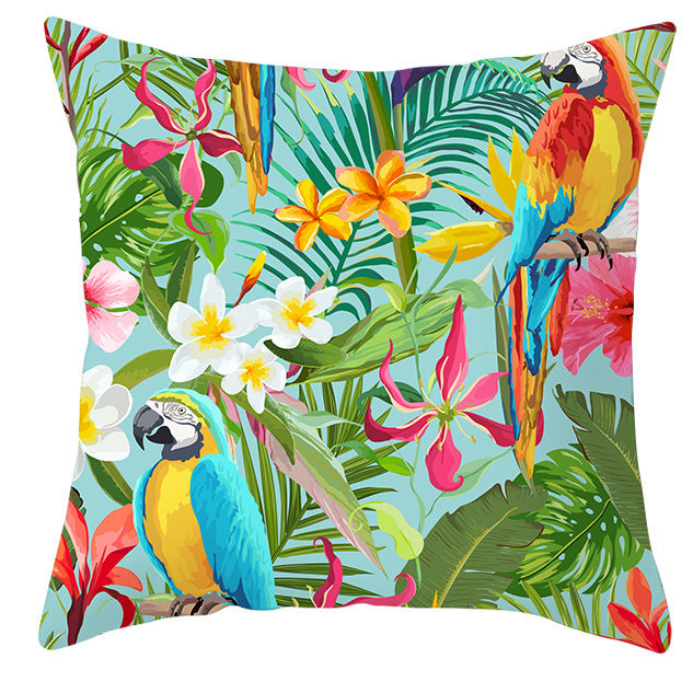 Decorative pillow with tropical design featuring parrots and flowers on a white background