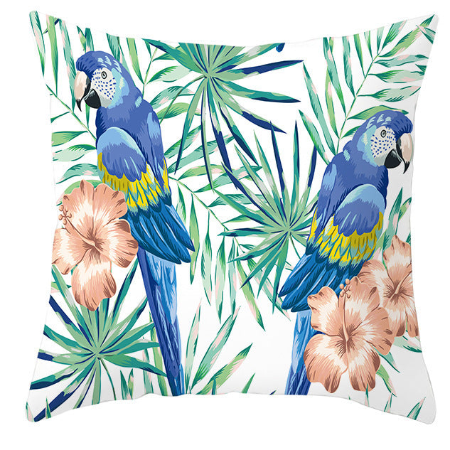 Decorative pillow with blue parrots and tropical leaves on a white background