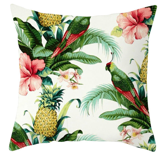 Decorative pillow with tropical design featuring parrots, flowers, and pineapples on a white background.