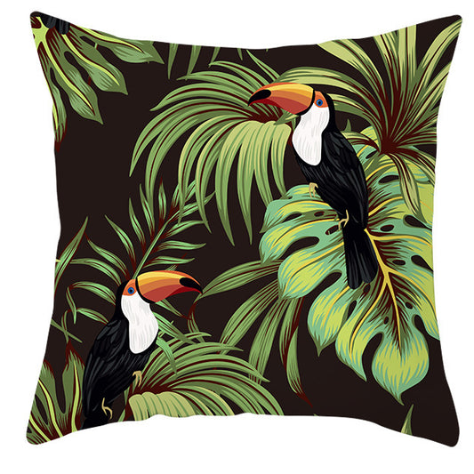 Decorative pillow with toucan and tropical leaf design on a black background