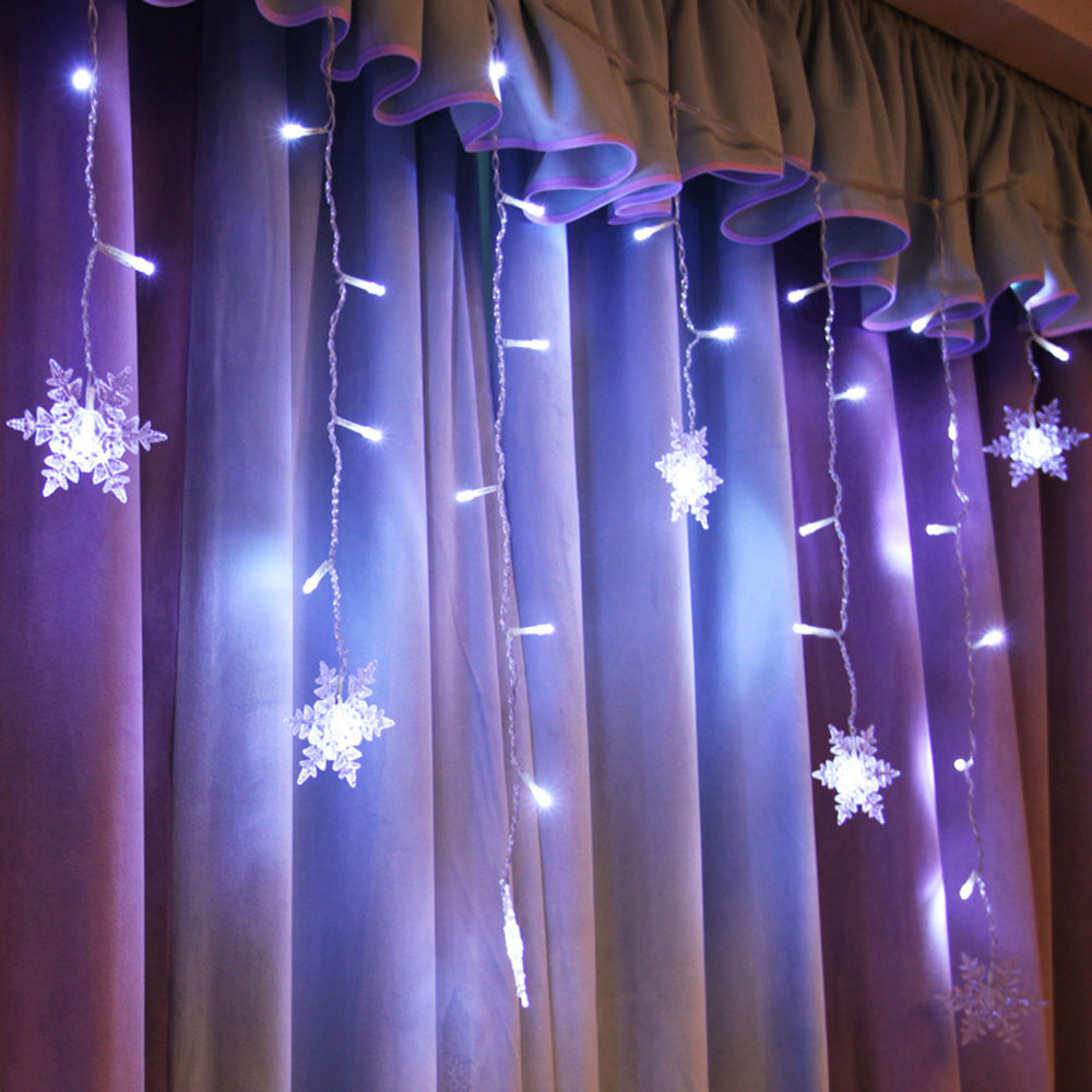 String lights shaped like snowflakes hanging on a curtain