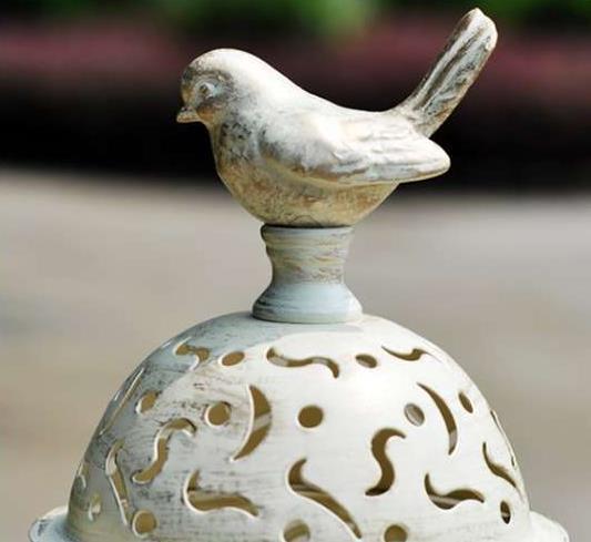 Decorative ceramic bird on top of a textured sphere with intricate patterns.