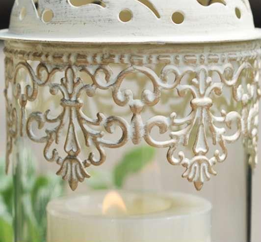 Decorative white lantern with intricate patterns holding a lit candle.