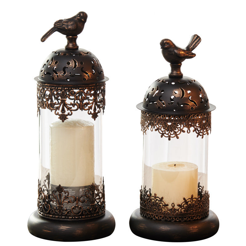 Two decorative candle holders with ornate designs and bird accents on a white background.