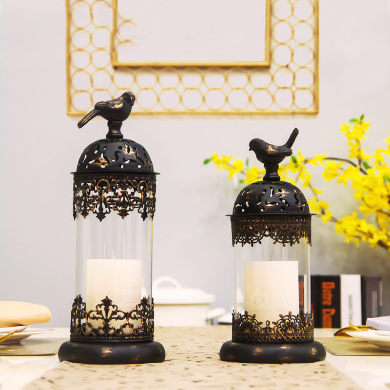 Decorative candle holders with bird designs on a table with a blurred background