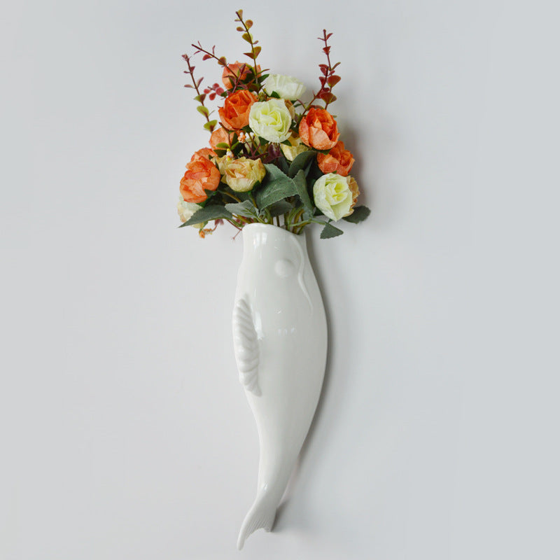 White wall-mounted vase with floral arrangement on a light gray background