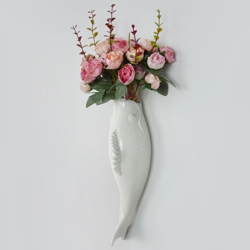 White wall-mounted vase with pink flowers on a light gray background