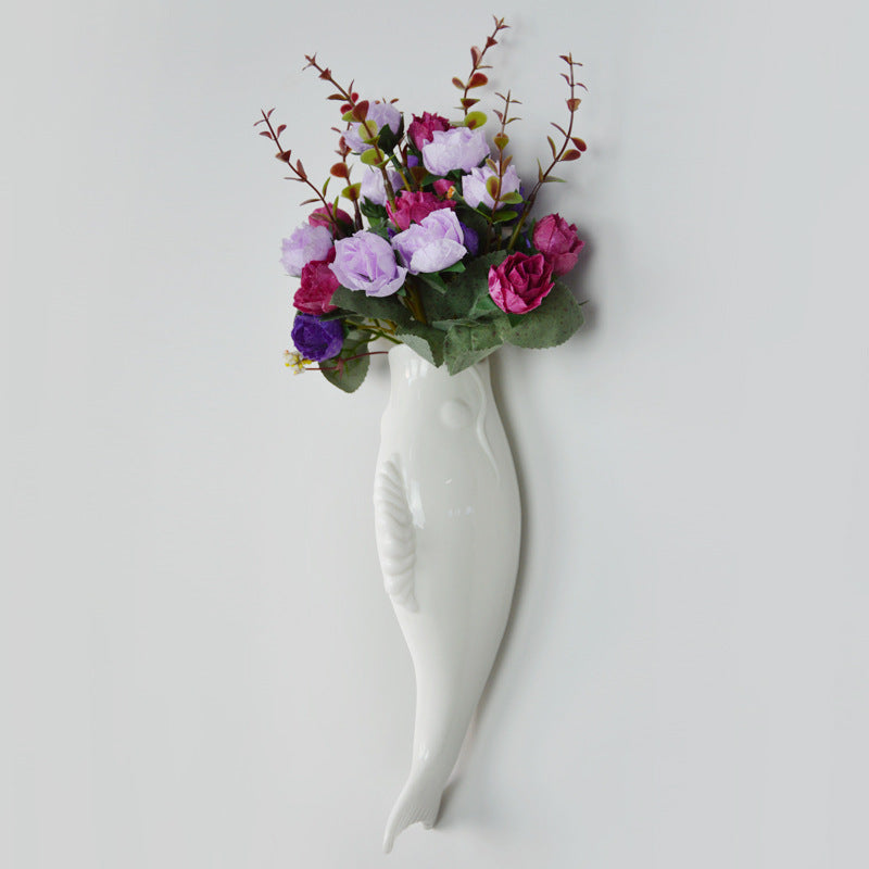 White wall-mounted vase with colorful flowers on a light gray background
