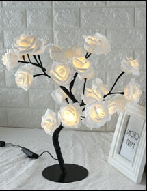 Decorative LED tree with white flowers on a gray surface.