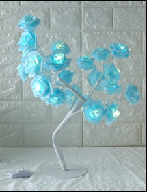 Decorative tree with blue flowers on a white stand against a textured wall.