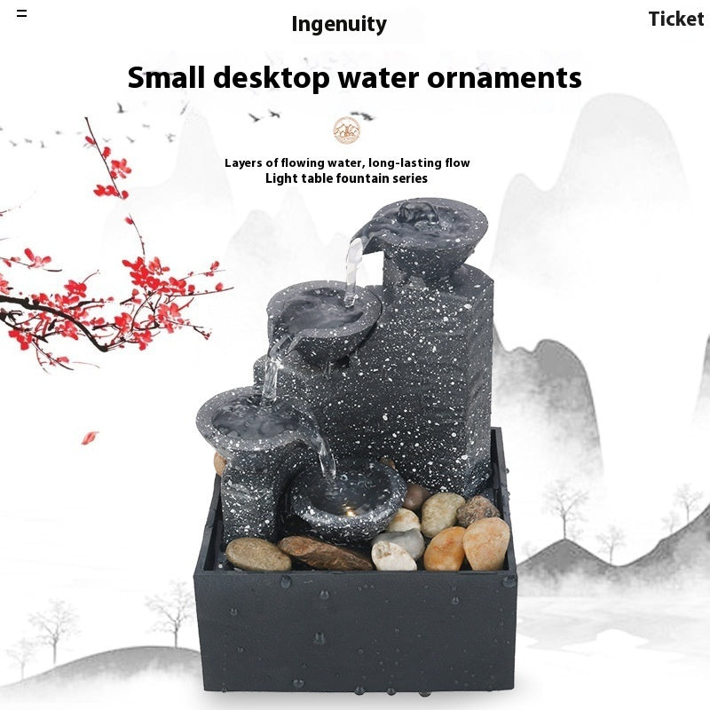Small desktop water ornament with flowing water and rocks on a white background
