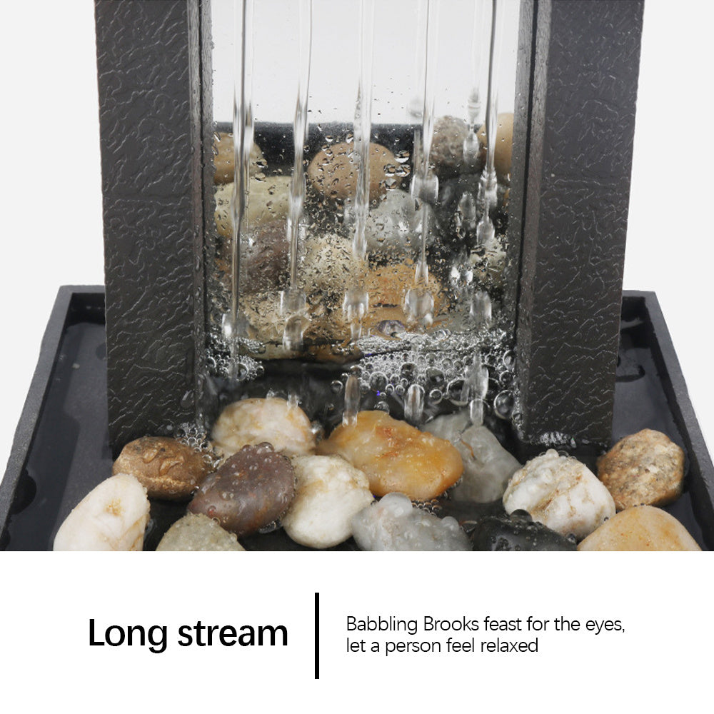 Fountain with rocks and water flowing through a glass cover on a white background