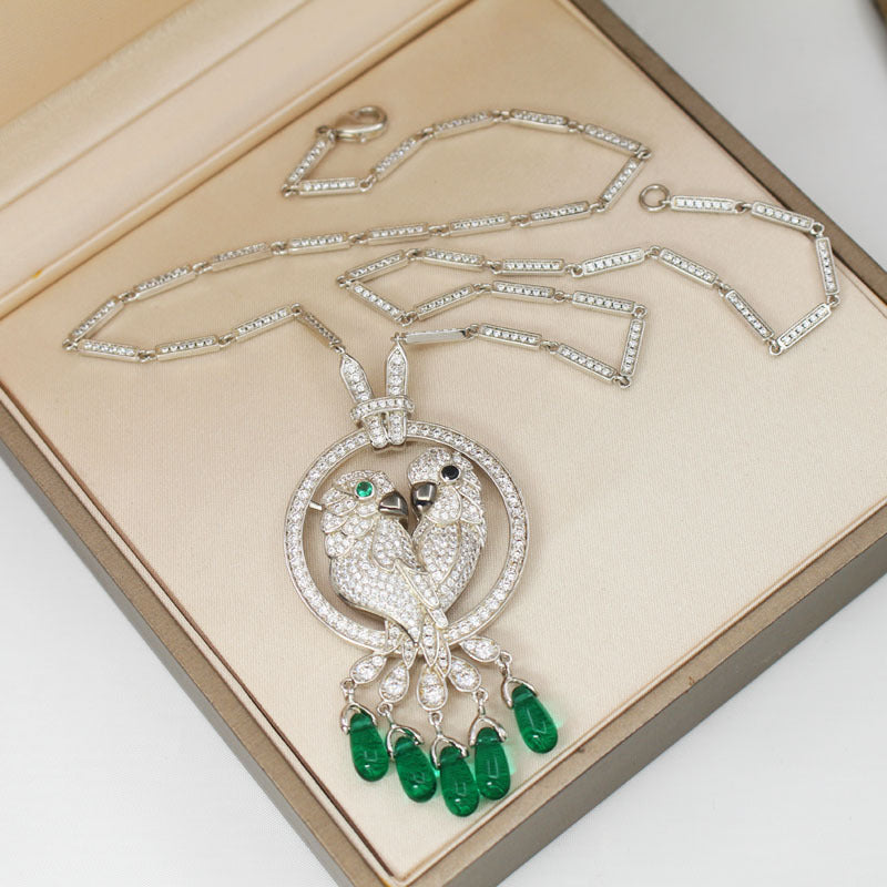 Ornate necklace with bird pendant and green gemstones on a beige background
