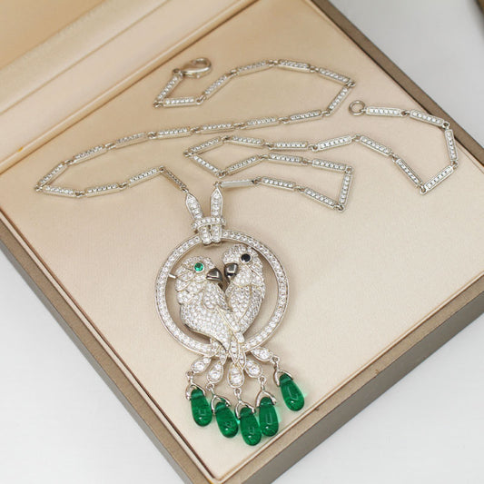Ornate necklace with bird pendant and green gemstones on a beige background