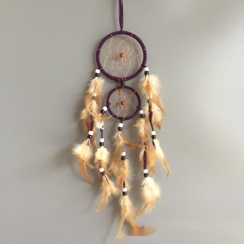 Dreamcatcher with feathers hanging against a plain background