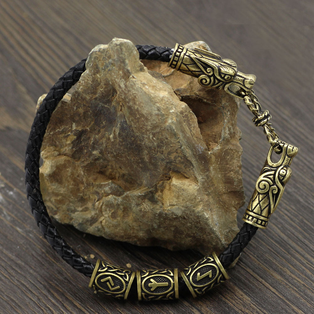 Bracelet with gold dragon clasp on a rock against a wooden background