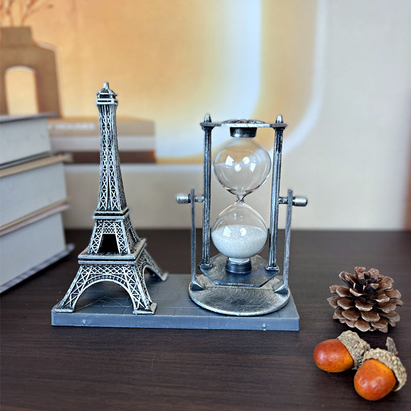 Decorative item with Eiffel Tower design and hourglass on a wooden surface.