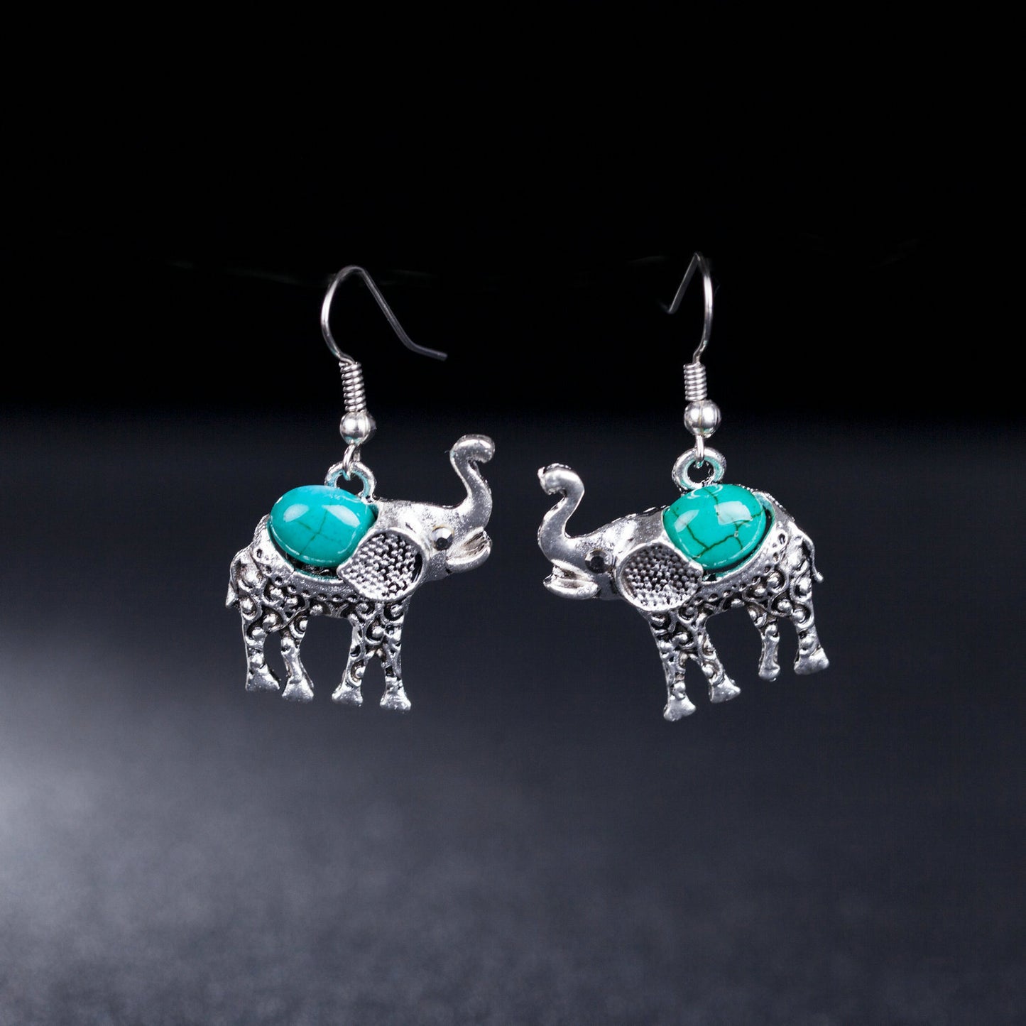 Silver elephant earrings with turquoise stones on a dark background