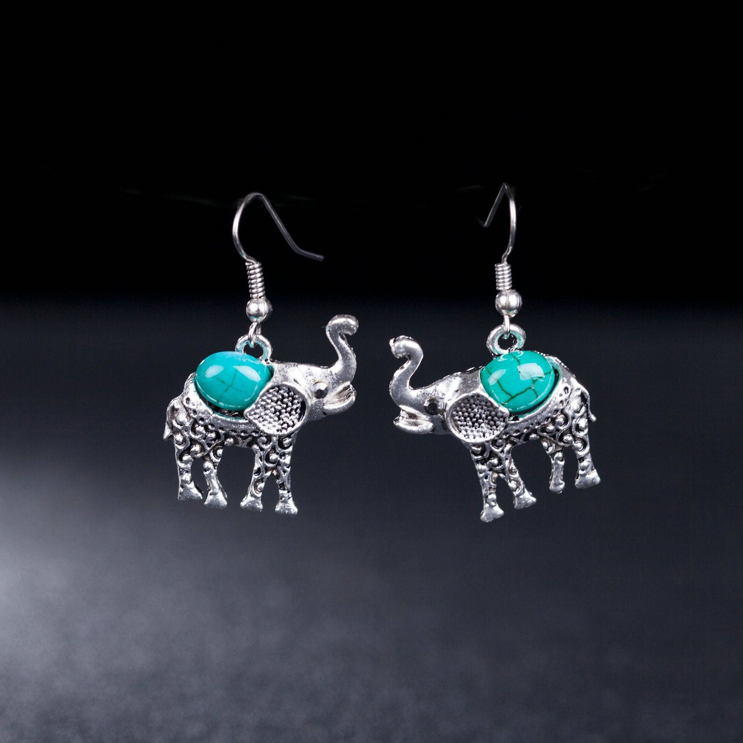 Silver elephant earrings with turquoise stones on a dark background