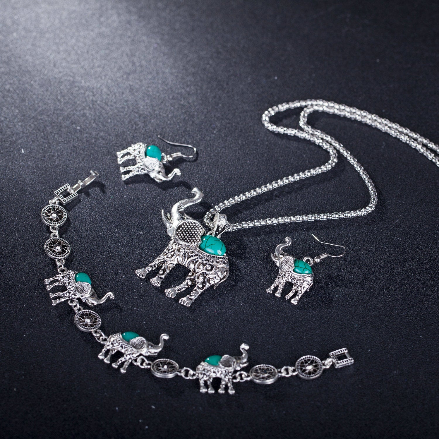 Silver elephant jewelry set with turquoise stones on a black background