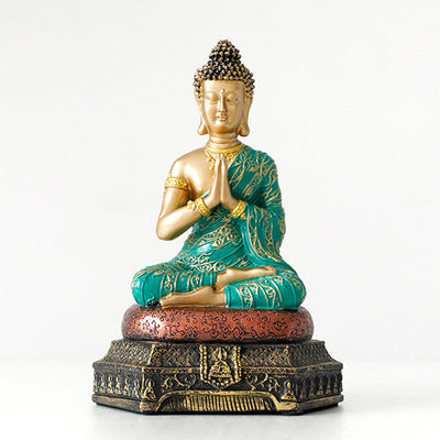Statue of a seated Buddha with green and gold coloring on a white background