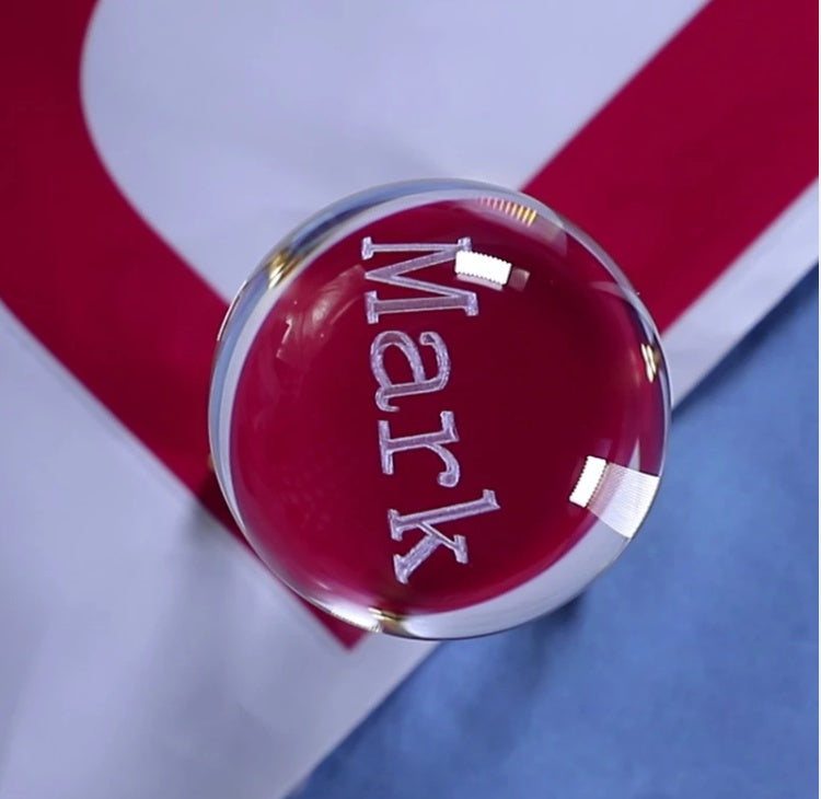 Clear glass knob with 'Mark' engraved on a red and white striped background
