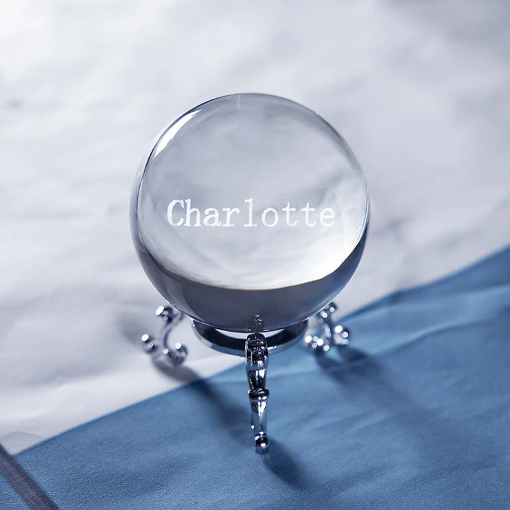 Crystal ball with 'Charlotte' engraved on a blue fabric background