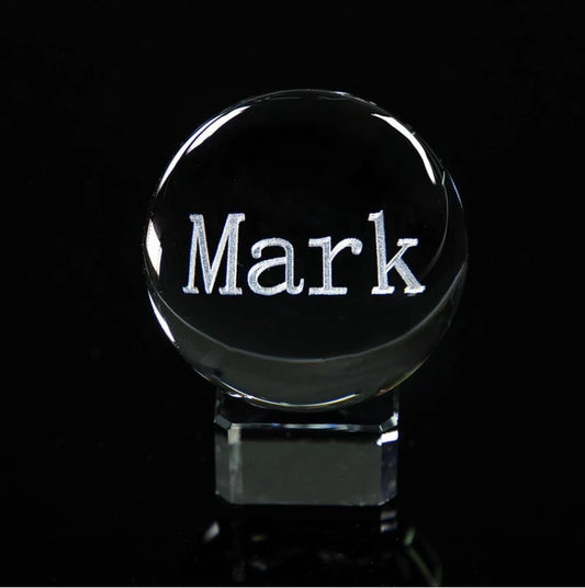 Clear crystal ball with 'Mark' engraved on a black background