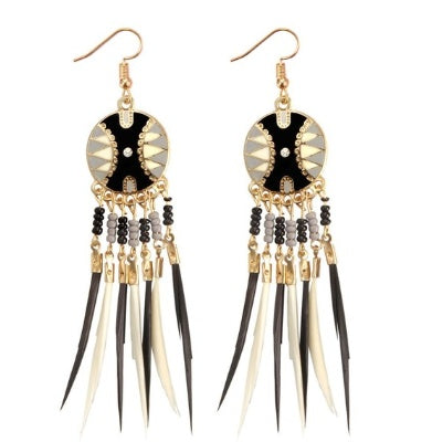 Pair of gold and black feather earrings with gold chains and decorative elements on a white background