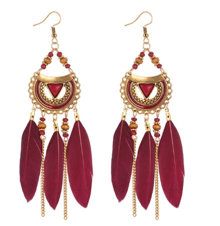 Feathered earrings with gold accents and red stones on a white background