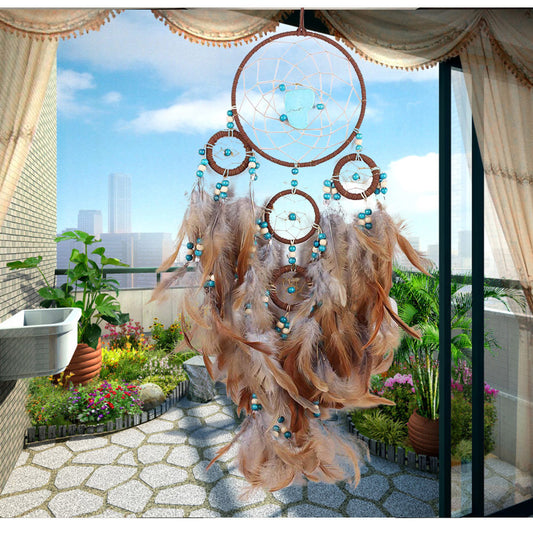 Dreamcatcher with feathers and beads hanging outdoors on a sunny day.