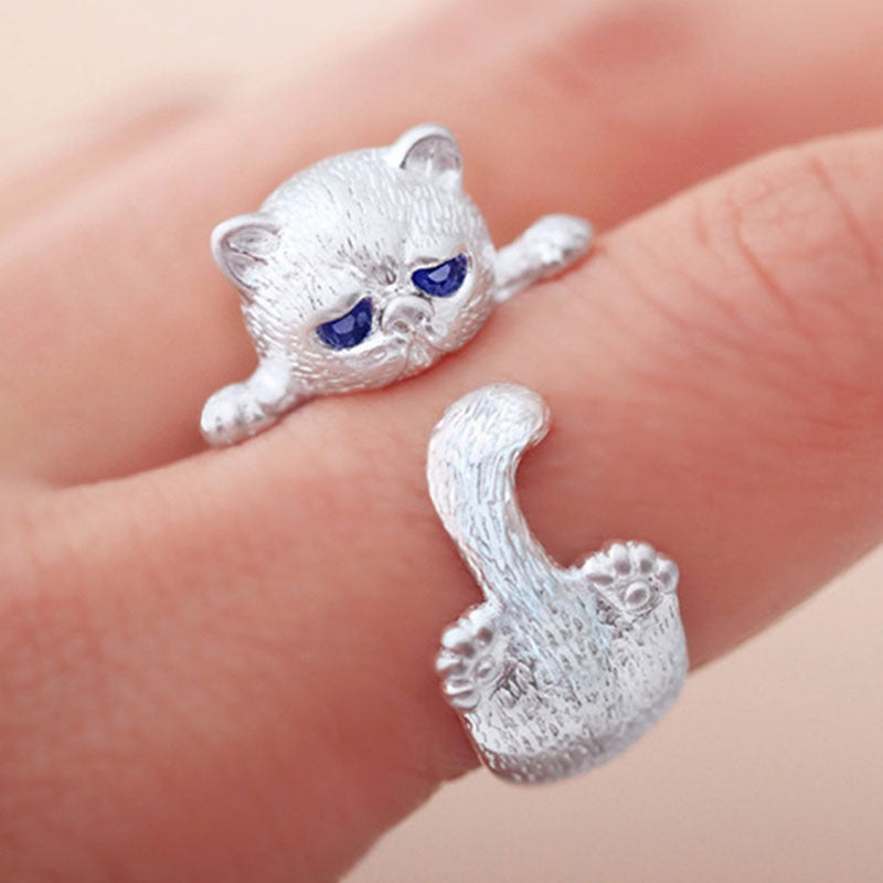 Silver cat-shaped earrings on a finger