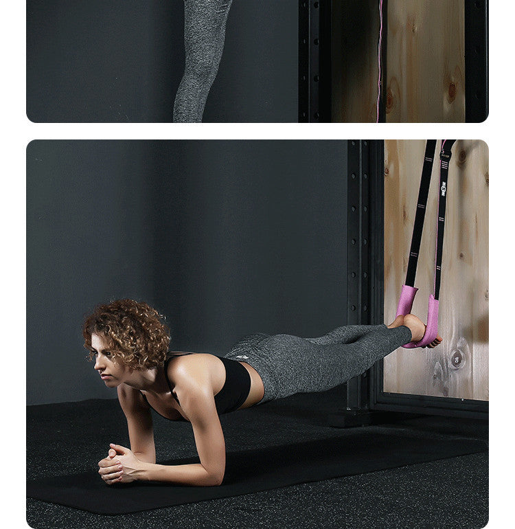 Woman performing a plank exercise with the help of TRX straps on a black mat.