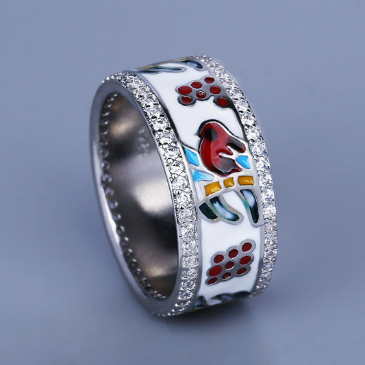 Silver ring with colorful bird design on a gray background