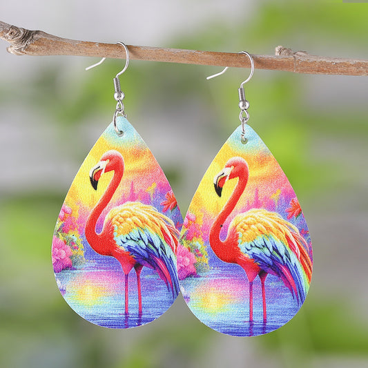 Teardrop-shaped earrings with colorful flamingo design hanging on a branch.
