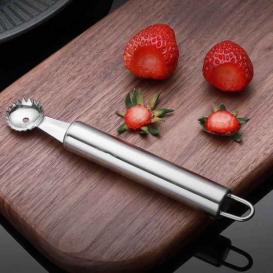 Strawberry huller on a wooden cutting board with strawberries