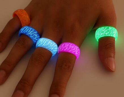 Hand wearing multiple colorful glowing rings on a neutral background