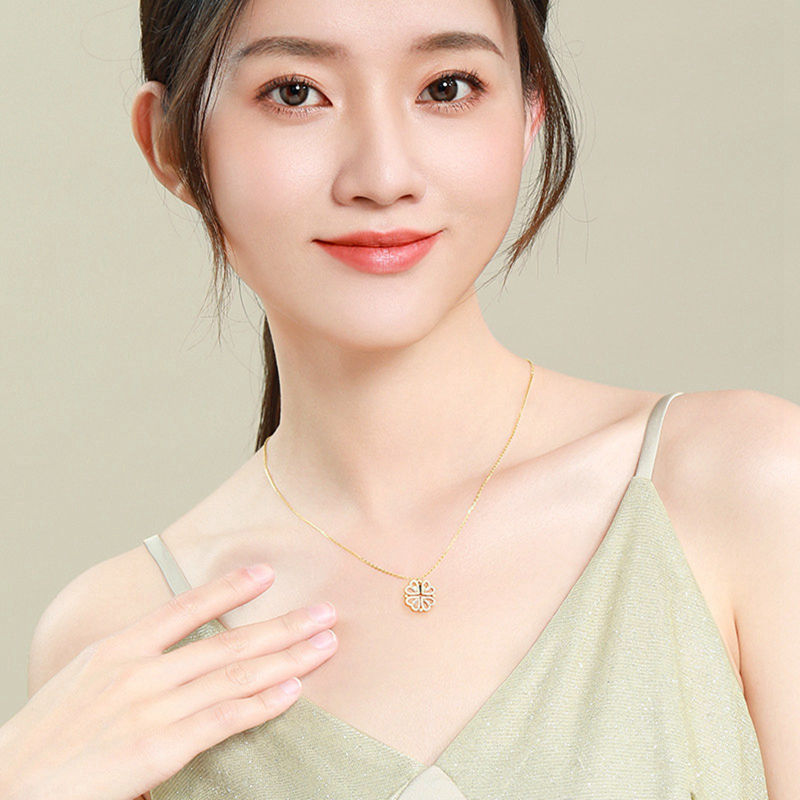 Woman wearing a gold necklace with a green top against a beige background