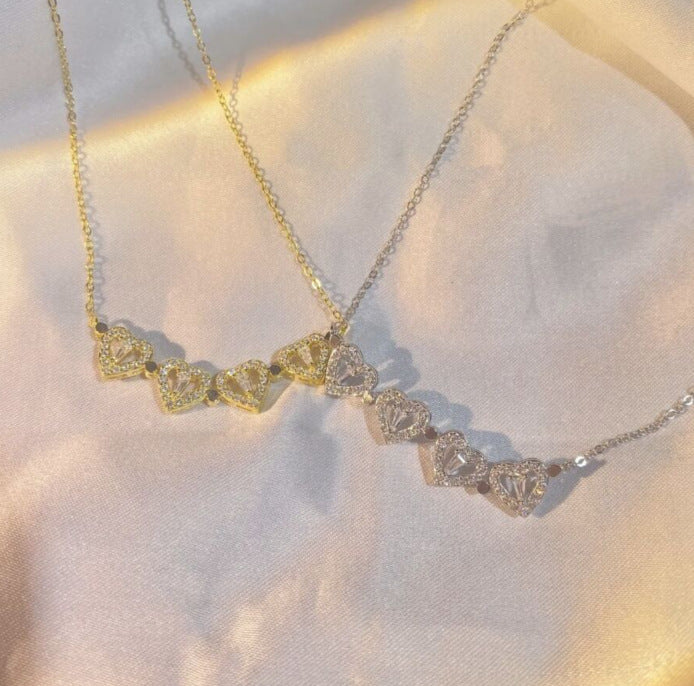 Necklace with heart-shaped diamond pendants on a soft fabric background