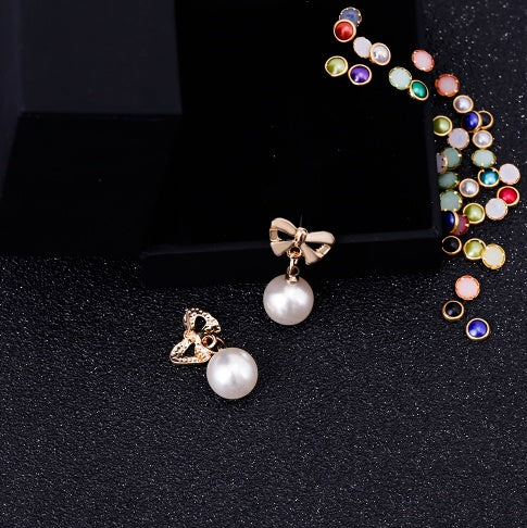Pair of earrings with pearl and bow design on a black background